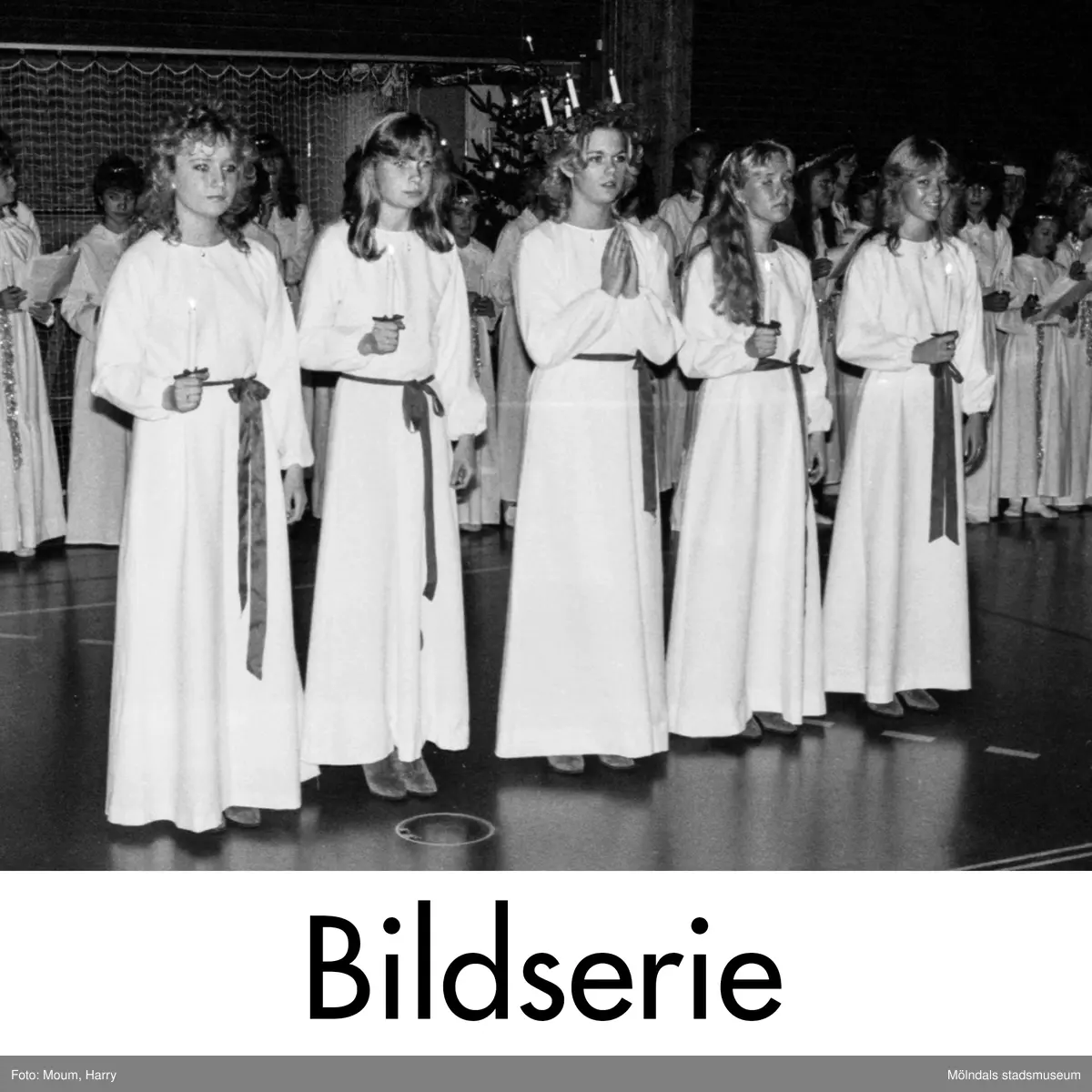 Serie om fem fotografier tagna av Harry Moum, HUM, för publicering till artikel i Mölndals-Posten, vecka 50, år 1983.

Här följer artikeln i sin helhet:
"Luciamorgon i Ekenskolan

Kållereds Lucia Agneta Larsson med tärnor besökte under morgontimmarna sin egen skola på Eken.

Samtliga elever, lärare, bambatanter och vaktmästare hade samlats i gymnastiksalen för att avvakta Lucians ankomst.

I mörker och medan skolans kör effektfullt sjöng i bakgrunden tågade Lucian in tillsammans med sina fyra tärnor.

Sedan sjöng de tillsammans med kören alla de kända rara Lucia-sångerna utan några nymodiga konstigheter.

Mycket populära var stjärngossarna. I synnerhet en av gymnastiklärarna som hade skrudat sig i en alldeles för kort nattskjorta. Därtill bara ben. En sällan skådad syn.

I all villervallan på Luciamorgonen så är det nog på sin plats att minna om själva legenden. Många har nog glömt bort den vid det här laget.

Lucia, som betyder ljus, är ett sicilianskt helgon, som enligt legenden skall ha lidit martyrdöden omkring 300. Hon var en ädelburen jungfru, i vars vackra ögon en hednisk yngling hade förälskat sig. Hon rev då ut dessa och sände honom dem på ett fat, varefter Gud gav henne ännu skönare ögon.

Lucias dag är den 13 december, som i Norden länge ansågs föregås av årets längsta natt.

Luciafirandet anknöt i vårt land tidigt till en rad hedniska föreställningar. Från 1700-talets mitt kommer seden med att låta en vitklädd kvinna åtföljd av tärnor tidigt på morgonen bjuda på välfägnad. Detta firande fick på 1930-talet sin stora publika karaktär i vårt land.

Hur som helst. Vackert är det.

HUM"