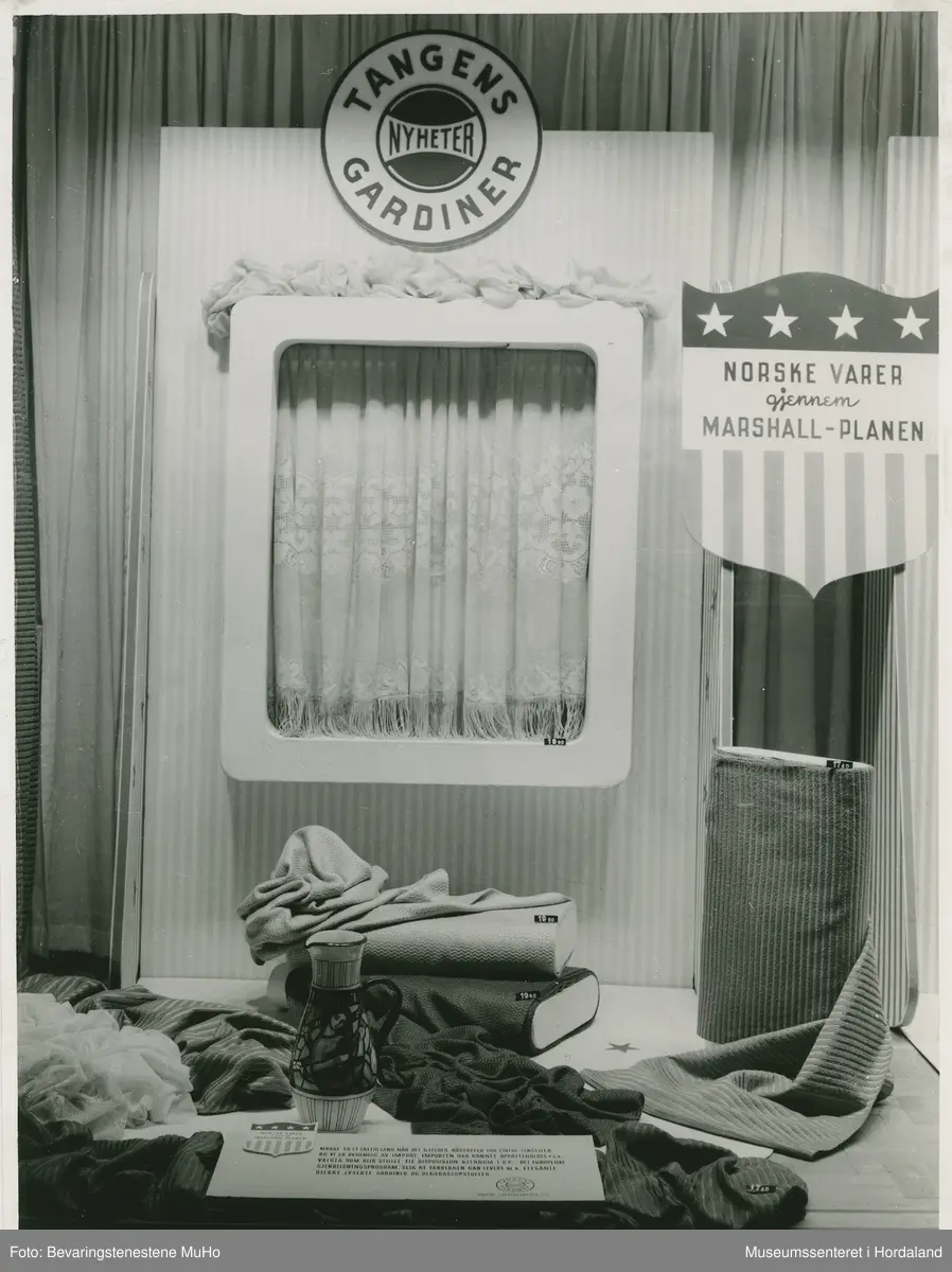 Utstillingsfoto frå Tangens Gardinfabrikk, Bergen. Foto frå ulike messe- og vindaugsutstillingar på 1920- til 60-talet. Bileta viser utstillingar av gardiner og møbelstoff frå bergensbedrifta.