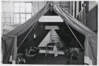 Försvarets dag 1942. 
Utställning i gymnastiksalen, I11. Information om sjukvårdstjänsten i fält. En uppbyggd bataljonsförbandsplats med mottagande avdelning.