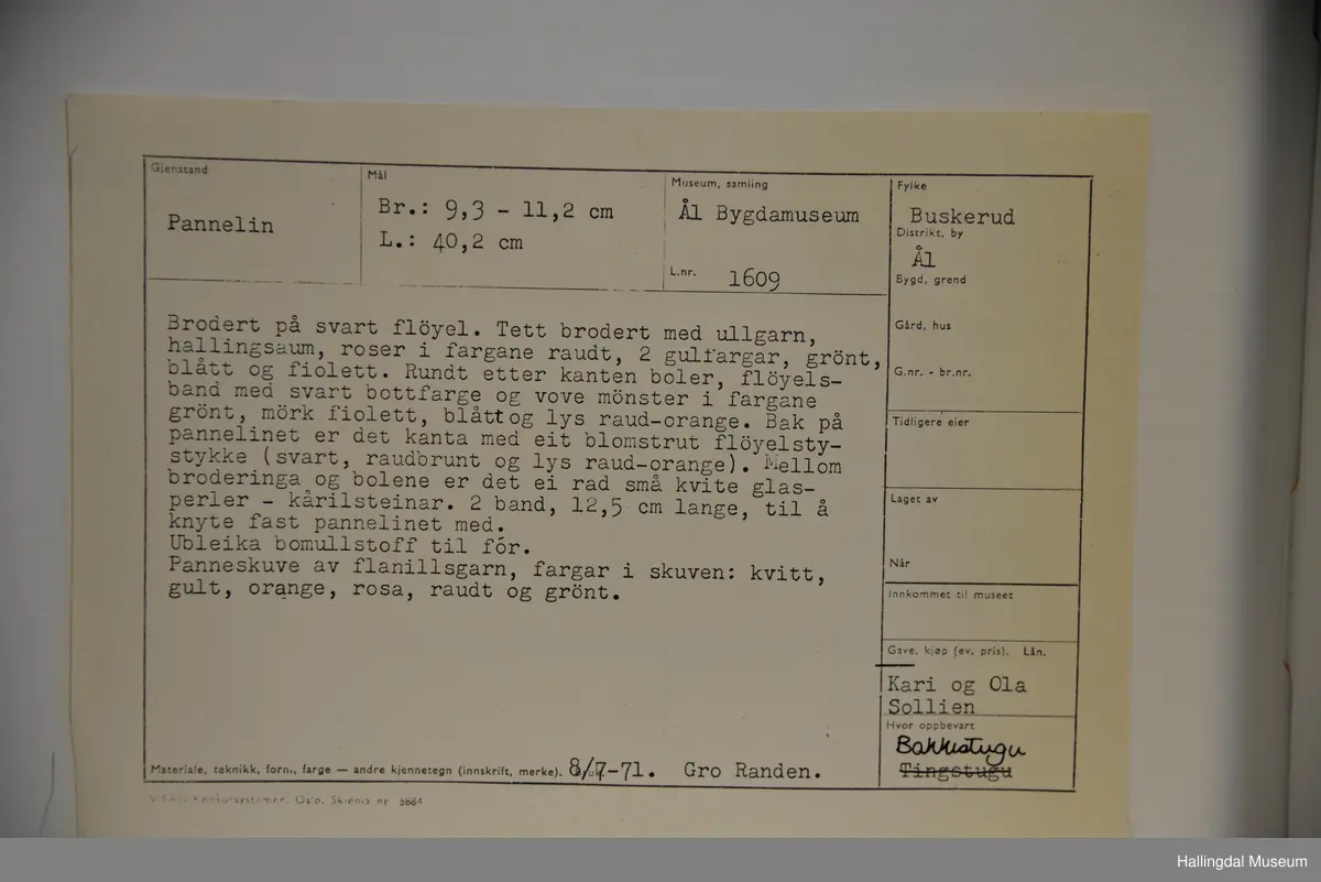 Brodert på svart fløyel. Tett brodert med ullgarn, hallingsaum, roser i fargene raudt, 2 gulfarger, grønt blått og fiolett. Rundt etter kanten boler, fløyelsband med svart bottfarge og vove mønster i fargane grønt og mørk fiolett, blått og lys raud-orange. Bak pannelinet er det kanta med eit blomstrut fløyelstykke (svart, raudbrunt og lys orange). Mellom  broderinga og bolene er det ei rad med perler - kårilsteiner. 2 band 12,5 cm lange, til å knyte fast pannelinet med. Ubleika bomullstoff til for. Panneskuve (dusk) av flanillgarn, fargear i skuven: kvitt, gult, orange, rosa og grønt.