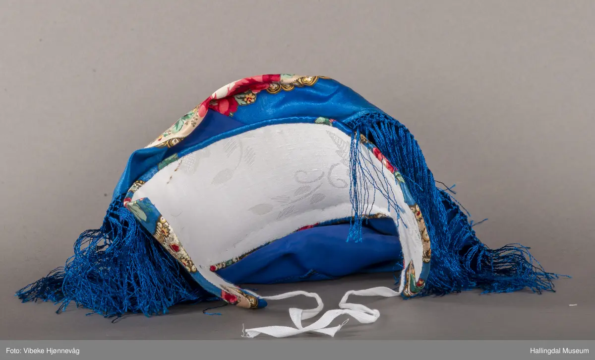 Halvsilkesateng. Sydd, trykt, kvit stiva heklet knipling. Blå bunnfarge, påtrykt blomster i alle farger.