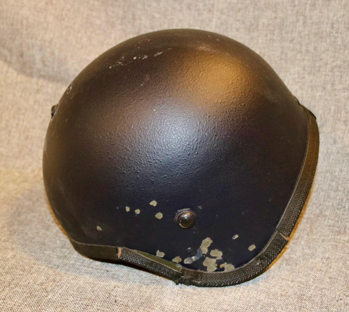 En sort sikkerhetshjelmmed skuddskader og en plastboks med hagl.