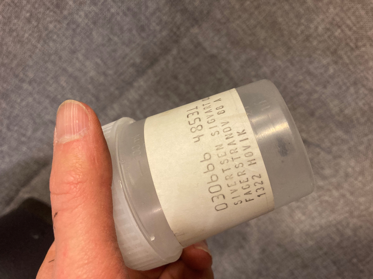 En sort sikkerhetshjelmmed skuddskader og en plastboks med hagl.