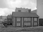 Vid Ågatans östra ände mot Hamngatan låg fastigheten Ågatan 2 till åtminstone det sena 1930-talet. Invid, bortom i bilden, låg det liknande bostadshuset Hamngatan 16. De bägge husen speglade en tidigare generations stadsbebyggelse och som länge hukade invid den nya tidens storskalighet. Brandväggarna talar sitt tydliga språk om en planerad utvidgning. Foto 1929.