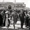 Jubileumsutställningen. 
Kronprinsparet Gustaf Adolf och Louise har just lämnat Smålands museum och går igenom Museiparken tillsammans med landshövding August Beskow. 

Kronprins Gustaf (VI) Adolf (1882-1973), reg. 1950-1973.
G. 2:o m. Louise, f. Mountbatten, (1889-1965).