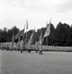 Jubileumsutställningen. Invigningen. 
Ett antal kvinnor i lottauniform tågar in på planen framför hedersläktaren.