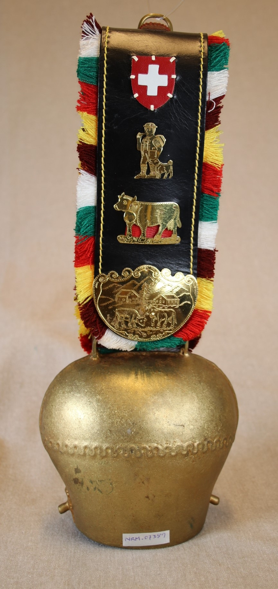 Våpenskjold med det sveitsiske flagget, et seterlandskap, en fjellvandrer og kyr.