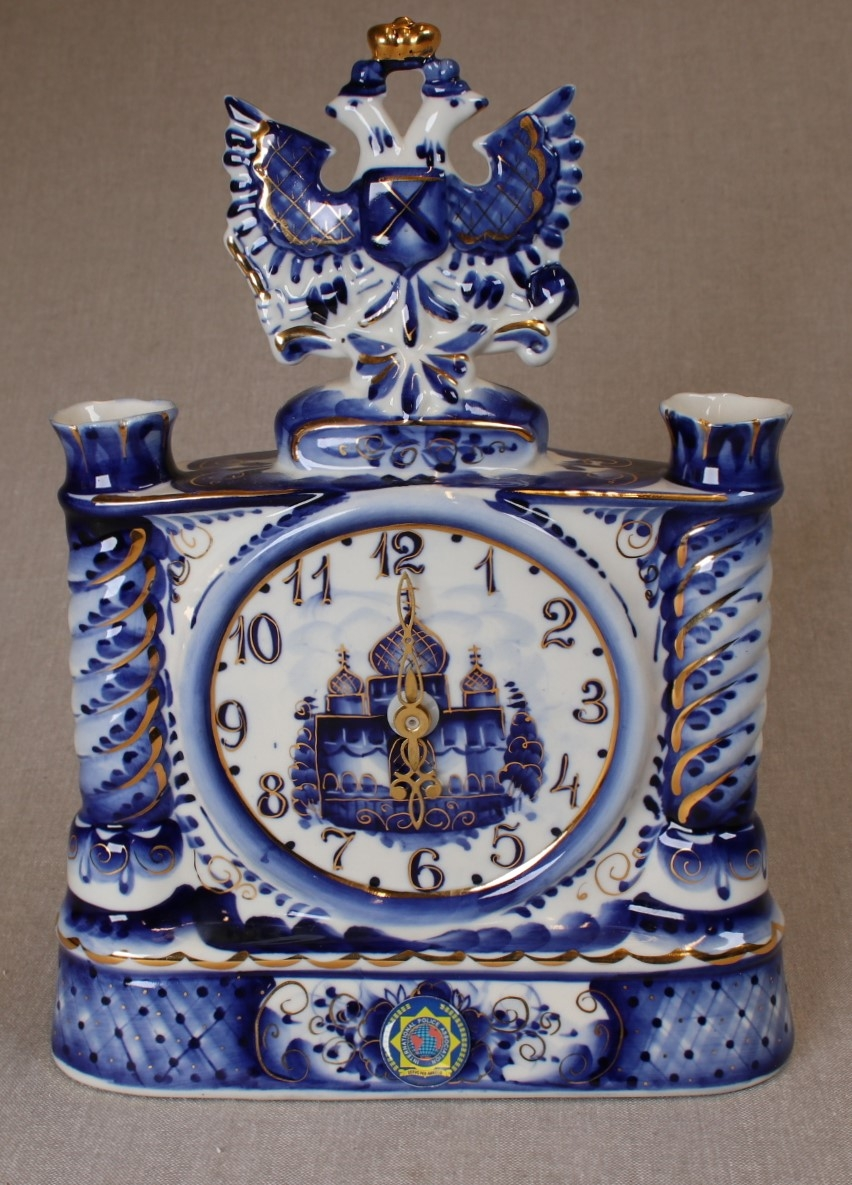 porselensur, hvitt med dekor i blått og gull. IPAs logo i front.
Dobbelørn med gullkrone på toppen.