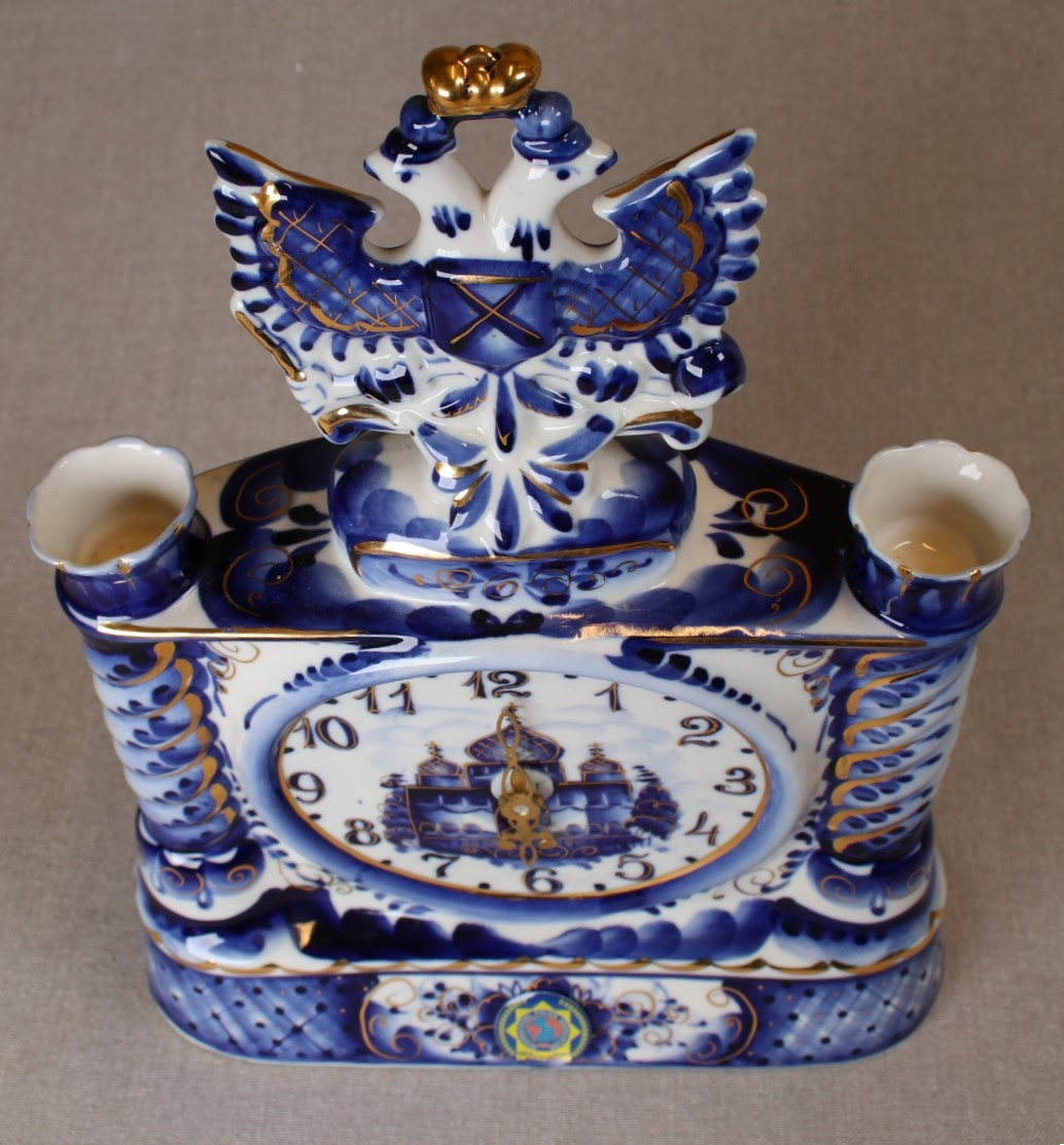 porselensur, hvitt med dekor i blått og gull. IPAs logo i front.
Dobbelørn med gullkrone på toppen.