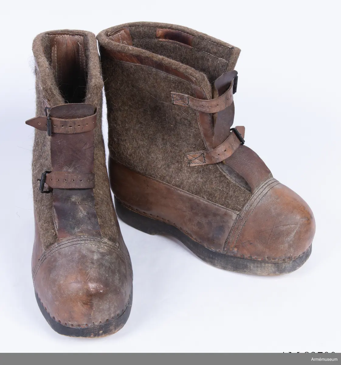 Gråbruna filtkängor med detaljer i brunt läder.

Ett par tyska vinterkängor för vakttjänst (Wehrmacht Winterstiefel), gjorda av tjocka träsulor fästa med rostig nubb till ovanläder (tåhätta, sidor samt hälkappa) av brunt skinn och skaft av tjock gråbrun valkat filt. Stövelskaften är kantade med en remsa brunt skinn.
Filten är mellan 1-1,5 cm tjock och tillverkad av valkad fårull, troligen iblandat hår från nötkreatur för större slitstyrka.
Sulan är gjord av ett ljust träslag och är mellan 3-3,5 cm tjock. Undersidan av sulan är obehandlad, medan sidorna är svartfärgade.
Kängorna har utanpåliggande plös av brunt skinn. Varje stövel stängs med dubbla läderremmar och svartlackade spännen.
På insidan av stövlarna sitter en etikett från tillverkaren med texten "Anton Bartowski Schuhfabrik, Berlin, S016, 1942".

Märkta på undersidan av träsulan med siffran 31.