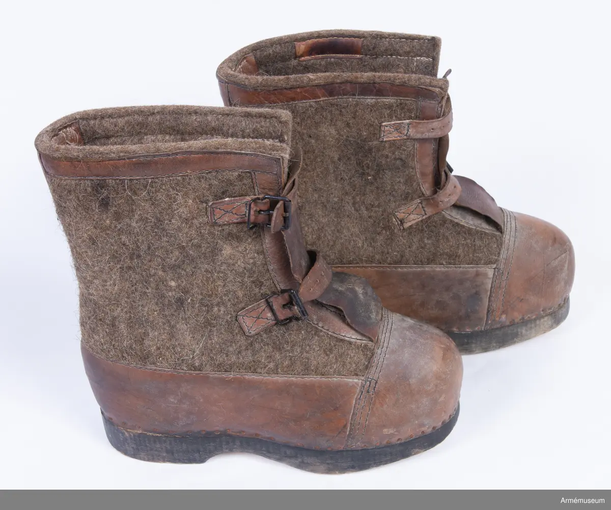 Gråbruna filtkängor med detaljer i brunt läder.

Ett par tyska vinterkängor för vakttjänst (Wehrmacht Winterstiefel), gjorda av tjocka träsulor fästa med rostig nubb till ovanläder (tåhätta, sidor samt hälkappa) av brunt skinn och skaft av tjock gråbrun valkat filt. Stövelskaften är kantade med en remsa brunt skinn.
Filten är mellan 1-1,5 cm tjock och tillverkad av valkad fårull, troligen iblandat hår från nötkreatur för större slitstyrka.
Sulan är gjord av ett ljust träslag och är mellan 3-3,5 cm tjock. Undersidan av sulan är obehandlad, medan sidorna är svartfärgade.
Kängorna har utanpåliggande plös av brunt skinn. Varje stövel stängs med dubbla läderremmar och svartlackade spännen.
På insidan av stövlarna sitter en etikett från tillverkaren med texten "Anton Bartowski Schuhfabrik, Berlin, S016, 1942".

Märkta på undersidan av träsulan med siffran 31.