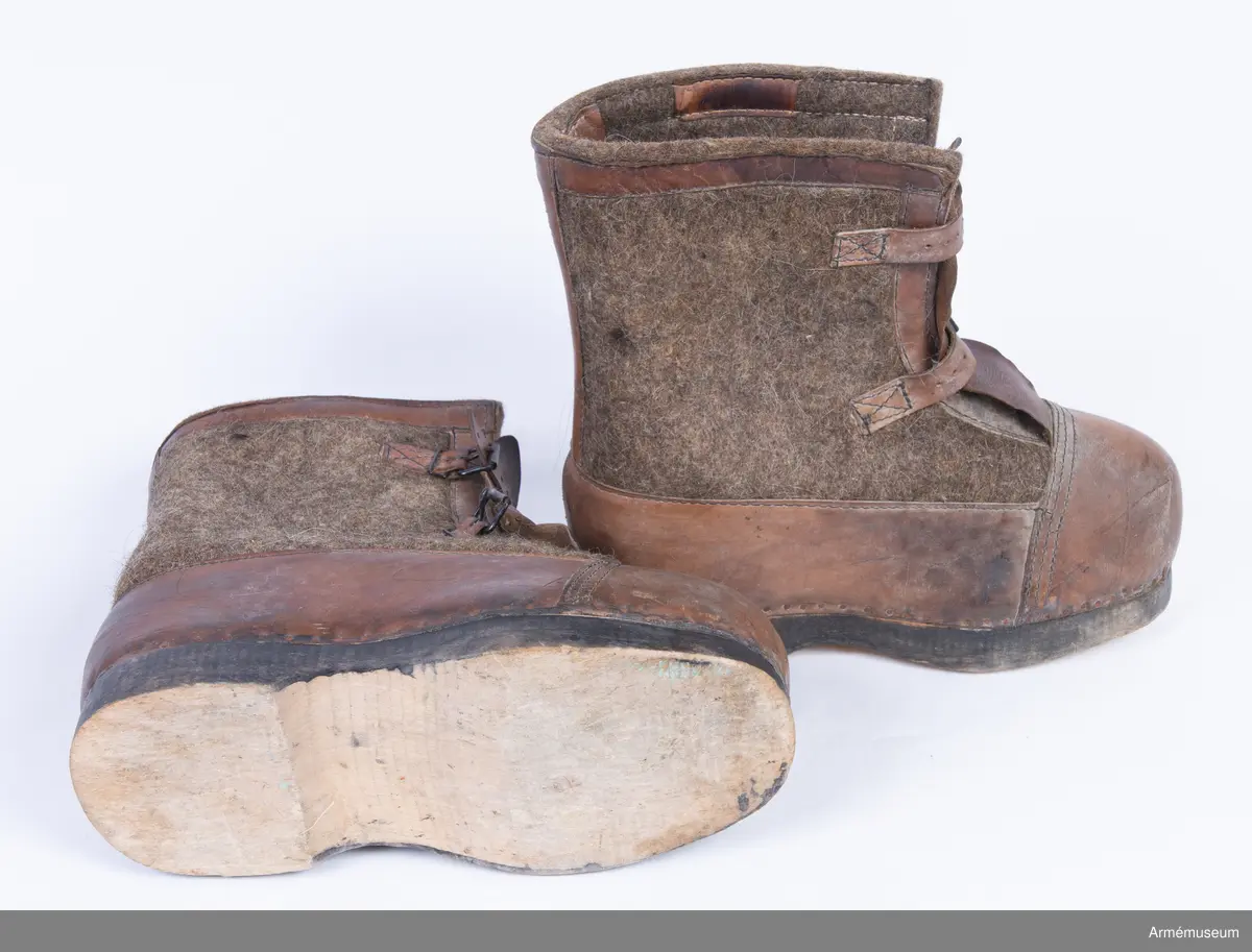 Gråbruna filtkängor med detaljer i brunt läder.

Ett par tyska vinterkängor för vakttjänst (Wehrmacht Winterstiefel), gjorda av tjocka träsulor fästa med rostig nubb till ovanläder (tåhätta, sidor samt hälkappa) av brunt skinn och skaft av tjock gråbrun valkat filt. Stövelskaften är kantade med en remsa brunt skinn.
Filten är mellan 1-1,5 cm tjock och tillverkad av valkad fårull, troligen iblandat hår från nötkreatur för större slitstyrka.
Sulan är gjord av ett ljust träslag och är mellan 3-3,5 cm tjock. Undersidan av sulan är obehandlad, medan sidorna är svartfärgade.
Kängorna har utanpåliggande plös av brunt skinn. Varje stövel stängs med dubbla läderremmar och svartlackade spännen.
På insidan av stövlarna sitter en etikett från tillverkaren med texten "Anton Bartowski Schuhfabrik, Berlin, S016, 1942".

Märkta på undersidan av träsulan med siffran 31.