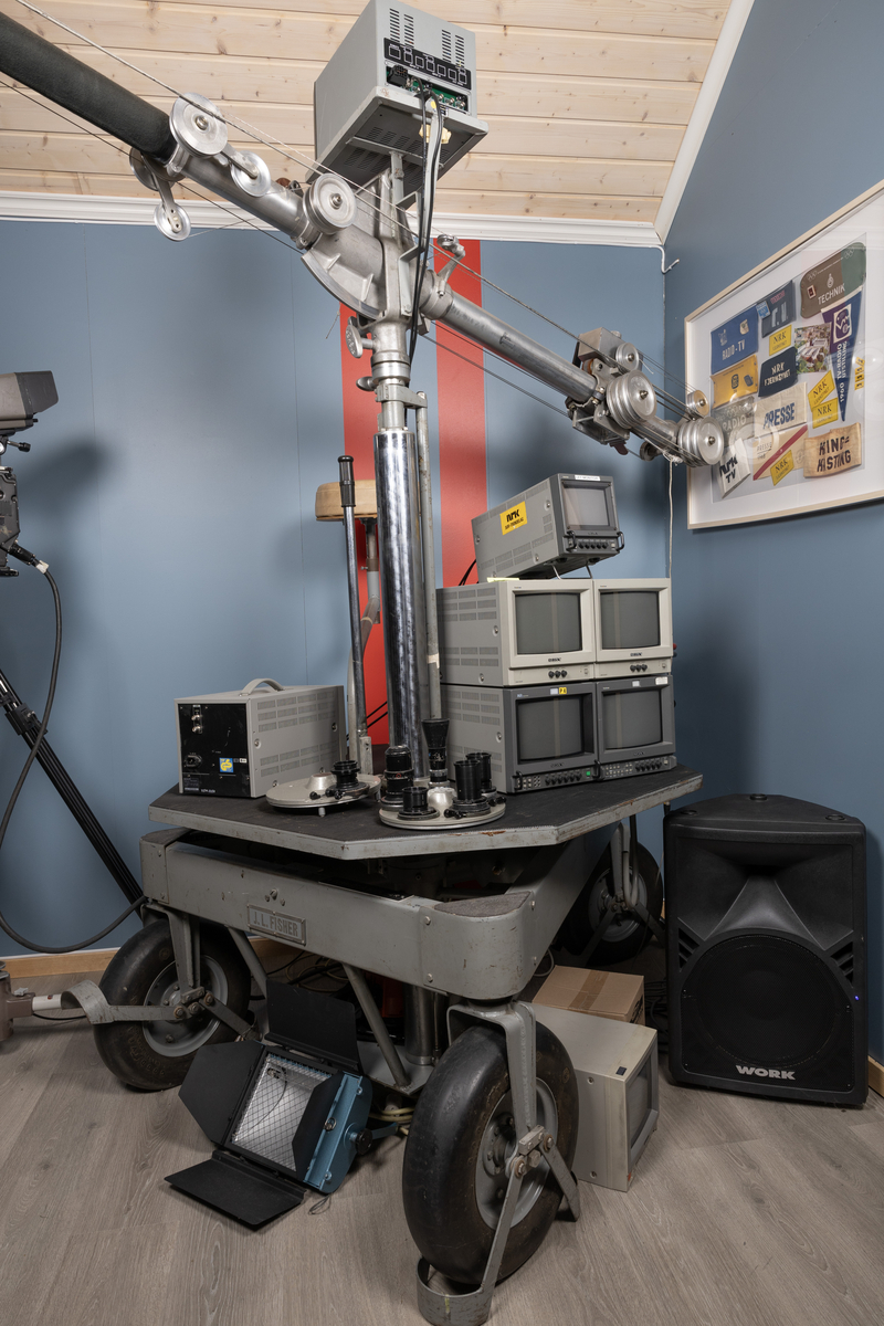 Teleskopisk mikrofonbom med ca.6 meters rekkevidde. Når den slås ut holdes den oppe av en motvekt for å være i balanse. Heises ut og inn alt etter behov. Plassert på bord med hjul og sete for operatør, samt tilhørende monitorer.