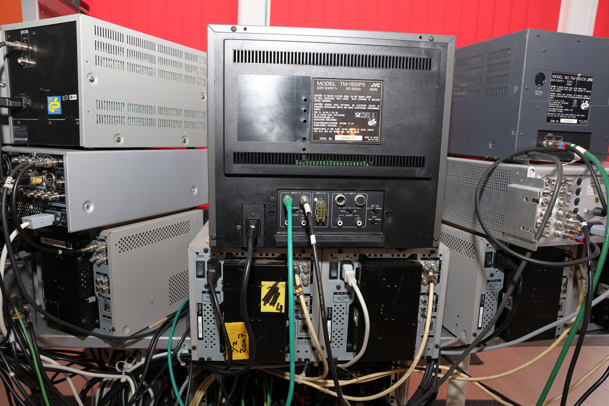Studio med miksebord og monitorer og separat rack med lydmikser.