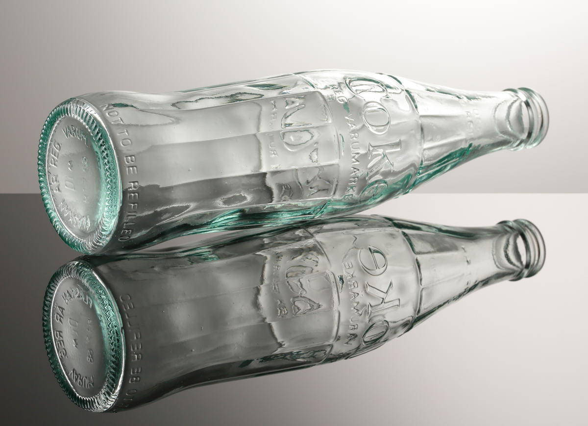 Coca-Cola flaska från Hammars glasbruk.
Maskinblåst i form. Följande text finns på flaskan: "Coke reg. varumärke". I relief: Ingen pant, ingen retur samt "Coca-Cola Reg. Varumärke". "Får ej fyllas på nytt. Not to be refilled".
Ljusturkost klarglas.

Inskrivet i huvudkatalogen 1968.