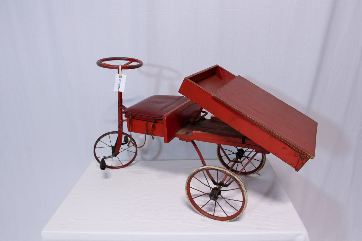 Rød metallsykkel med trehjul og lasteplan.