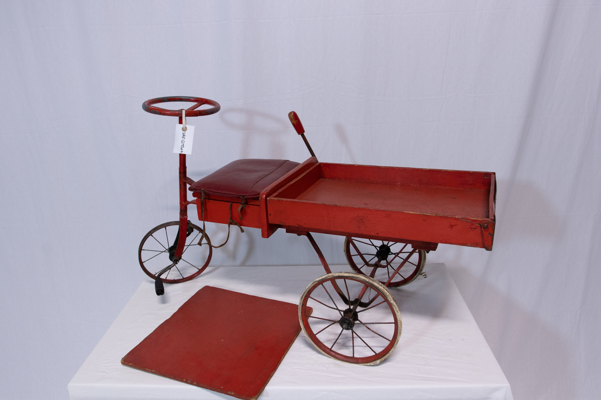 Rød metallsykkel med trehjul og lasteplan.
