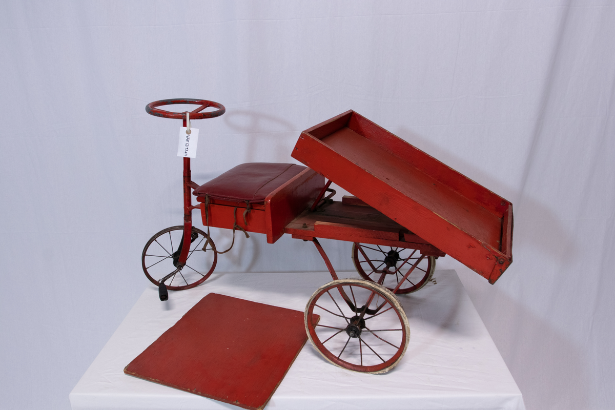 Rød metallsykkel med trehjul og lasteplan.