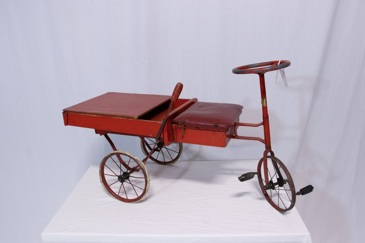 Rød metallsykkel med trehjul og lasteplan.