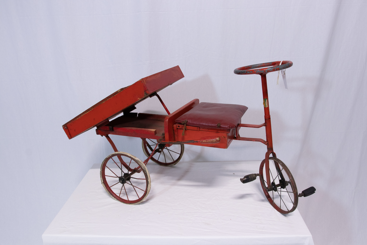 Rød metallsykkel med trehjul og lasteplan.