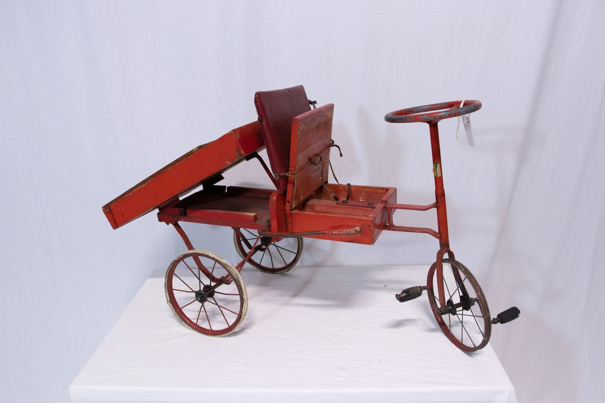 Rød metallsykkel med trehjul og lasteplan.