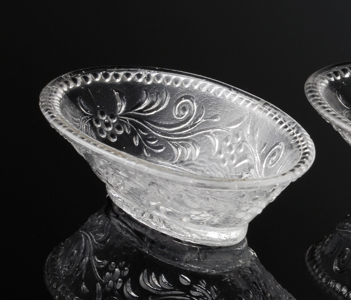 Glasskål, till dockservis.
Oval.
Pressglas.
Dekor: Blommönster.