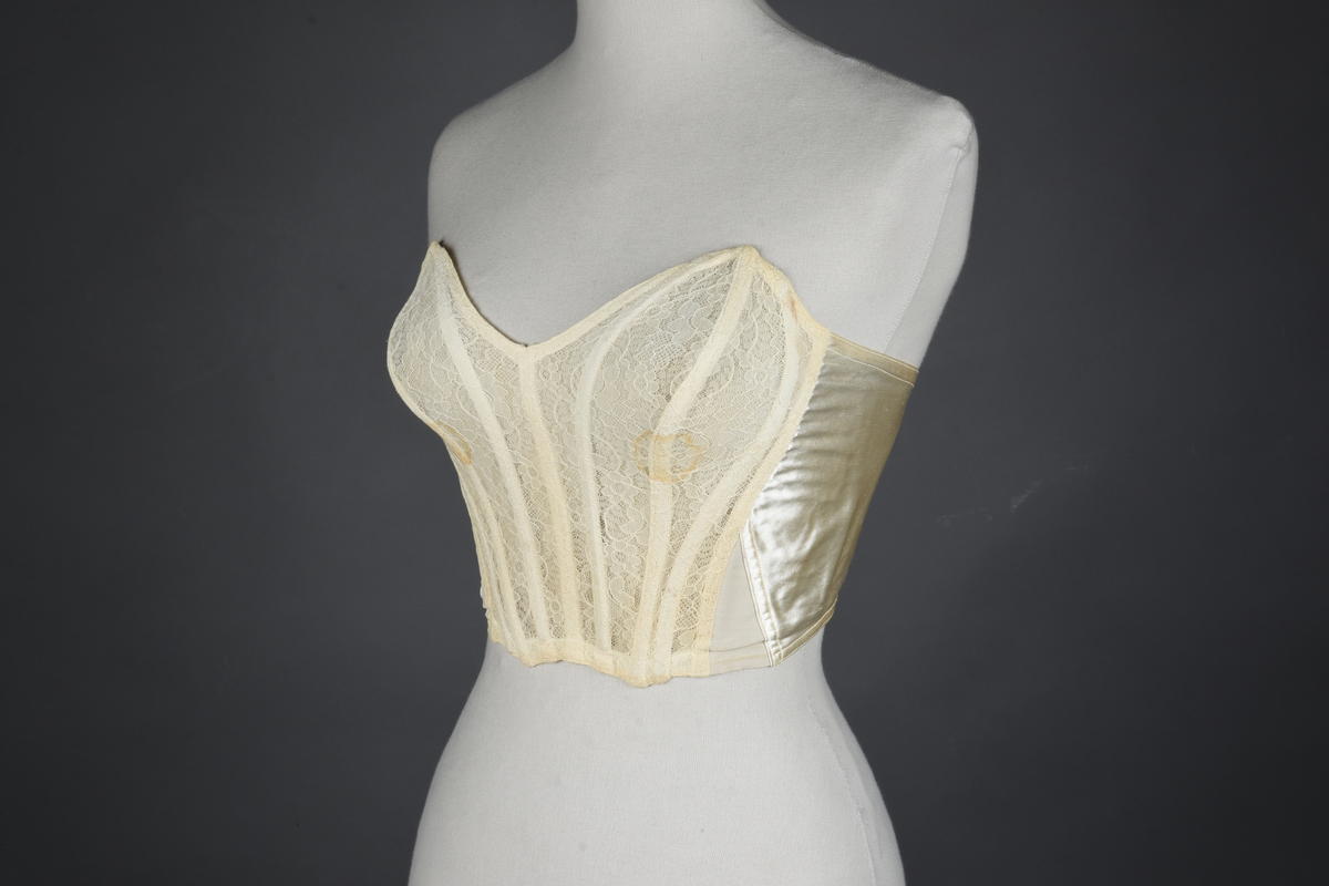 Brystholder med spiler. Lang i formen og kan minne om et korsett. Lukkes bak med hekter.