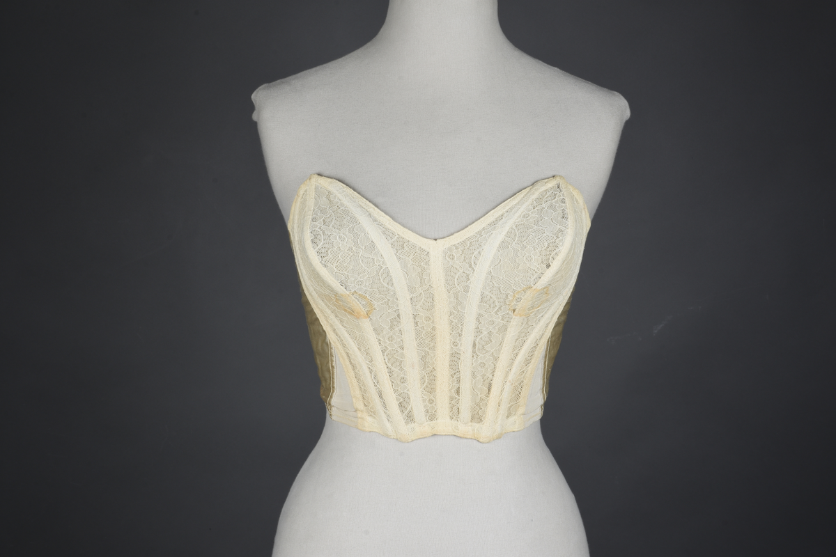 Brystholder med spiler. Lang i formen og kan minne om et korsett. Lukkes bak med hekter.