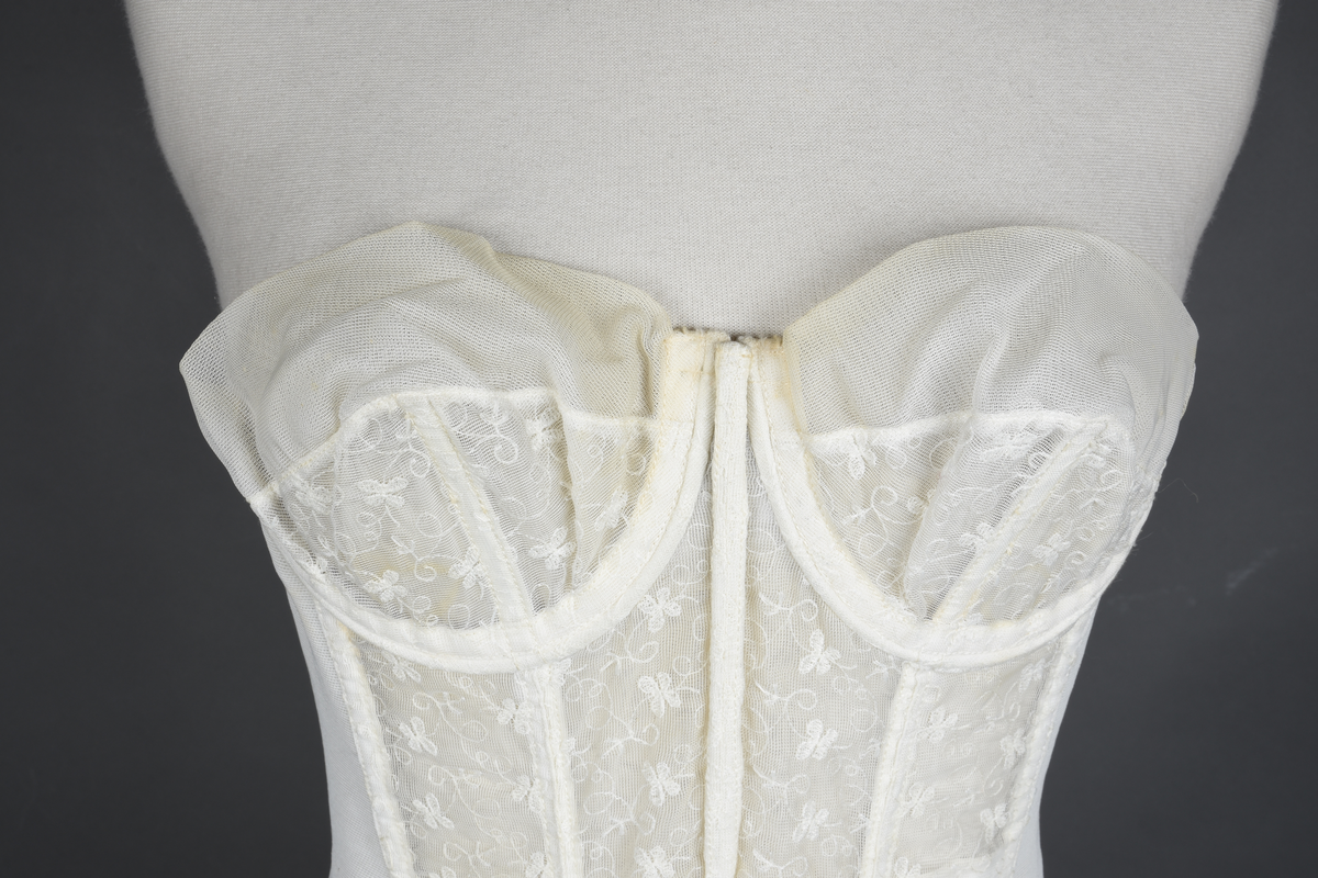 Brystholder av blondestrikk, med spiler. Både korsettspiler og cup-spiler. Lang form. Lukkes bak med hekter.