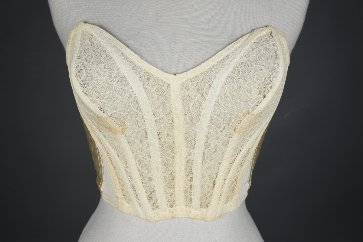 Brystholder med spiler. Lang i formen og kan minne om et korsett. Lukkes bak med hekter.