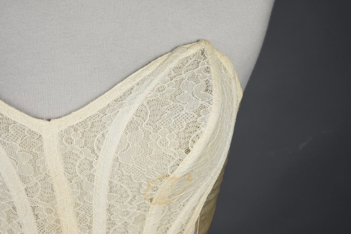 Brystholder med spiler. Lang i formen og kan minne om et korsett. Lukkes bak med hekter.