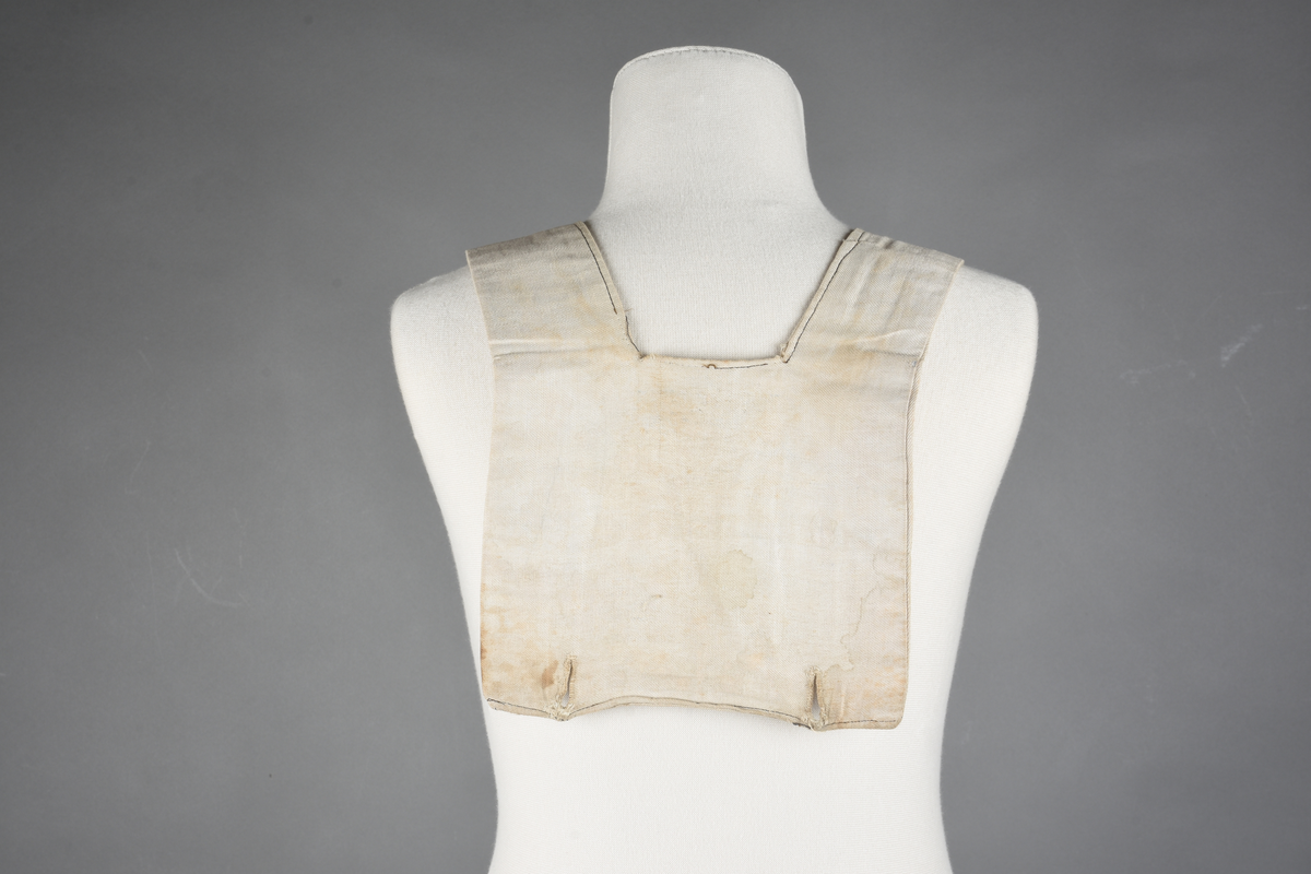 Matrosdress av ull og bomull. Bluse (A), benklær (B), livstykke (C) og matroskrave (D). Bluse med rett form og snøring i halsen. Legg på ermene. Lomme med rødt lommetørkle. Rød snor om skulder, Flagg- og våpenmerke. Benklær/bukse er åpen med knapp i begge sidene. Knelengde. Tre knappper på hvert bein, seks oventil. Grått livstykke til å feste buksen på. Knapphull og hemper. Matroskrave av mørkeblå silke med fire hvite striper langs den ytre kanten. To sorte bendel-knytebånd.