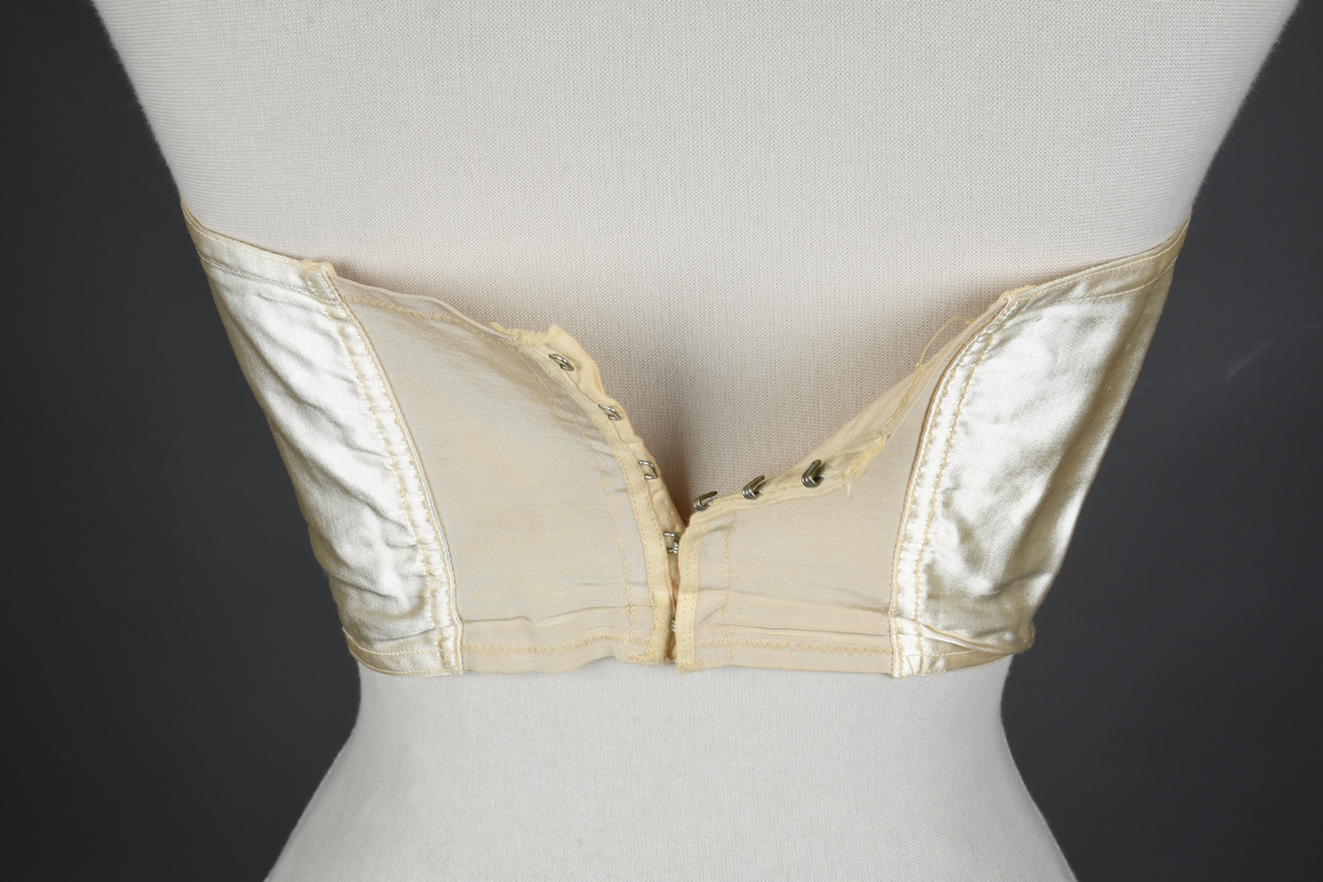 Brystholder med spiler. Lang i formen og kan minne om et korsett. Lukkes bak med hekter.