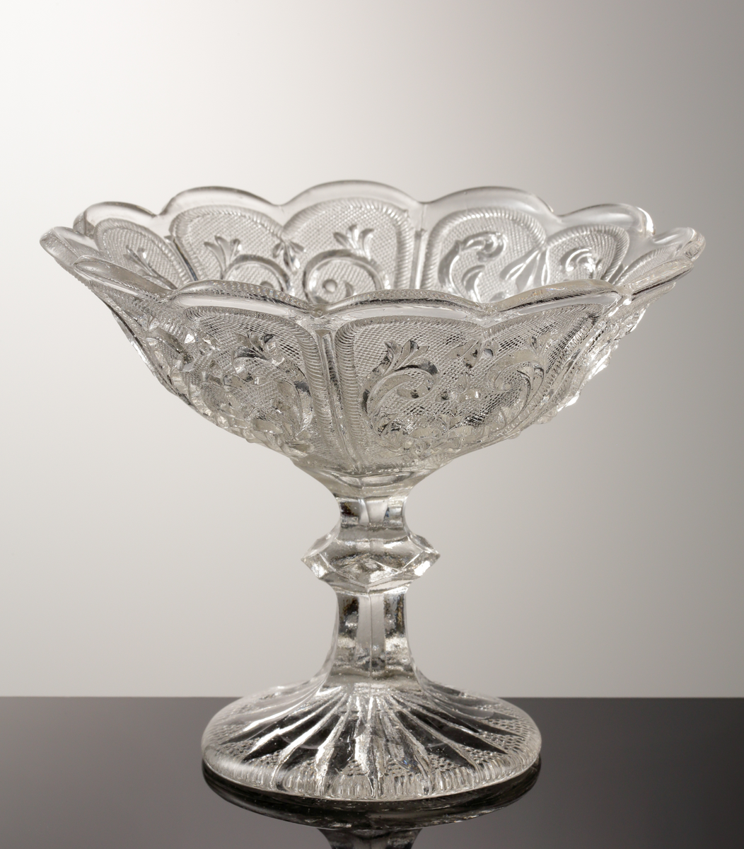 Skål, på ben och fot.
Pressad.
Klarglas.
Inpressat "Å".