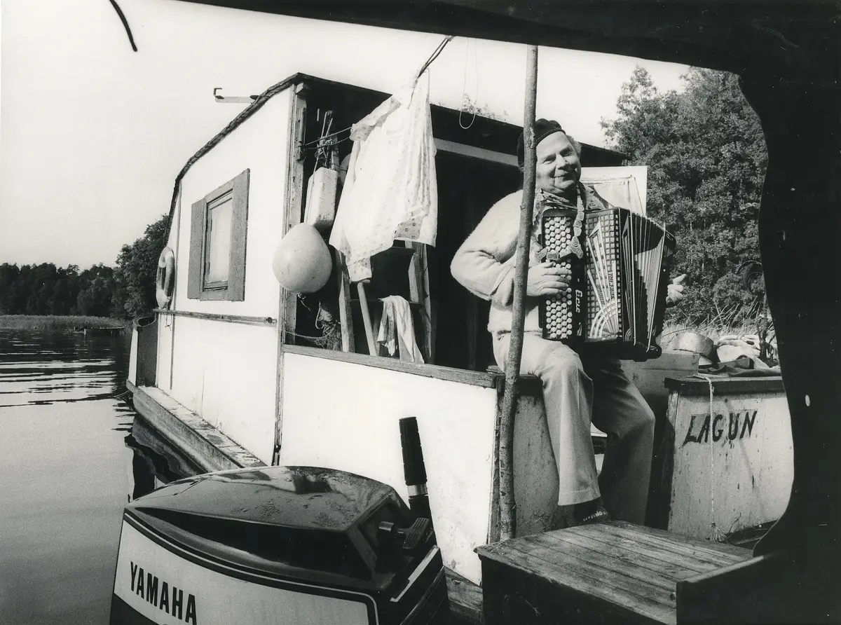 Bilden visar en man med smeknamnet "Småland" som bodde på sin husbåt längst in i Skutviken, bredvid Stäkets motorbåtsvarv (som ägdes av Sven Bergfeldt. "Småland" bodde på husbåten under 1960- och 70-talet. Foto tidigt 1970-tal. 