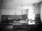 Kvinna sitter vid skrivbord, okänt kontor i Växjö. Ca. 1920.