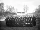 Klassfoto. Skolklass med fröken utomhus, med skolan i bakgrunden. Ca. 1900.