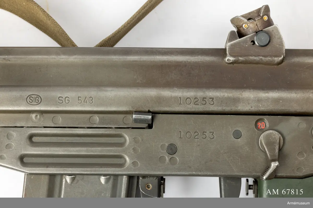 Tillverkningsnummer 10253.  Längd axelstödet i infällt läge 580 mm. Pipans längd med mynningsbroms 328 mm.
Vapnet märkt med (SIG) SG 543. Bestående av: 1 st automatkarbin, 1 st gevärsrem av väv.