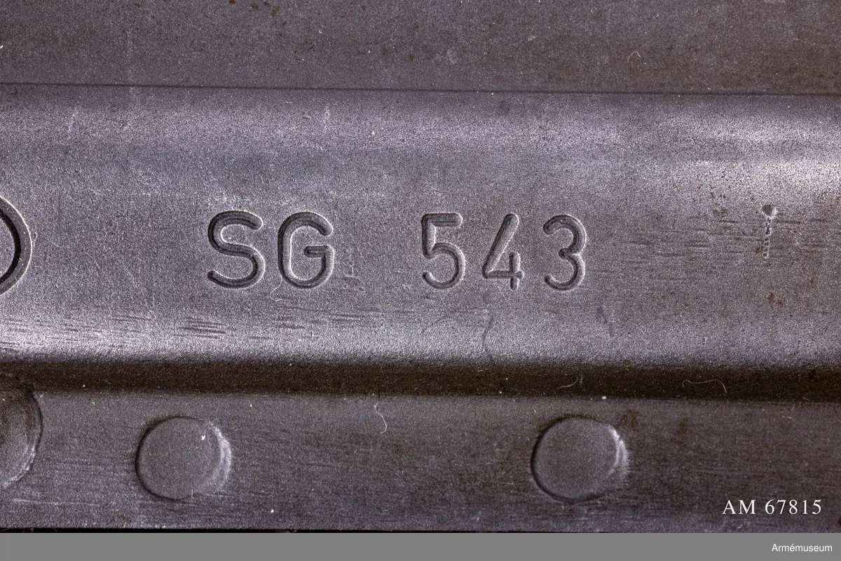 Tillverkningsnummer 10253.  Längd axelstödet i infällt läge 580 mm. Pipans längd med mynningsbroms 328 mm.
Vapnet märkt med (SIG) SG 543. Bestående av: 1 st automatkarbin, 1 st gevärsrem av väv.