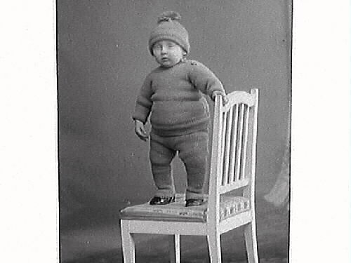 Liten pojke på två bilder i olika kläder med en stol. Gustaf Antonsson Södergatan 16, Varberg beställde bilderna och är troligen barnets far.