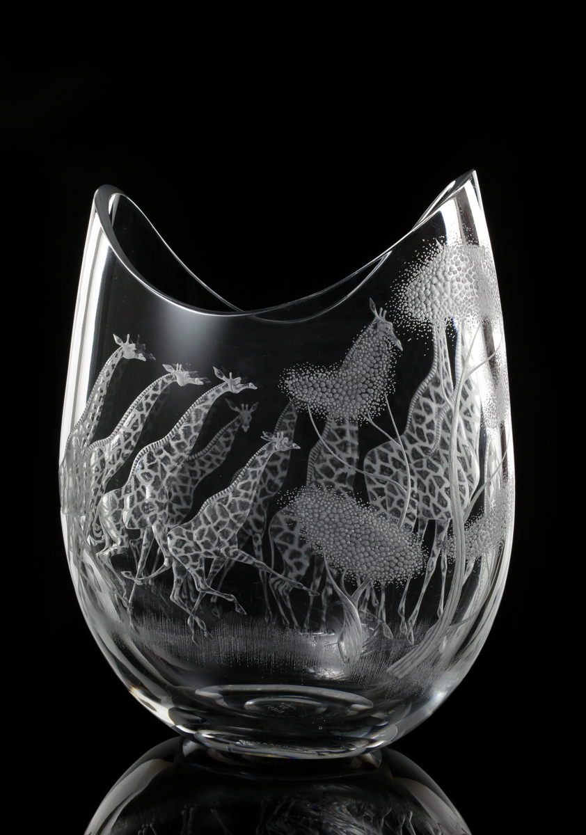 Vas. "Safari". LG 248, 22. Designer: Vicke Lindstrand.
Tillplattat slutet äggformat (oval), med vågigt nedbuktande överkant som är sågad.
Giraffer och träd i omvänd relief.
Ofärgat klarglas.
Väggtjocklek: 8 mm. 

Inskrivet i huvudkatalogen 1966. 

Kataloger:
Katalog nr. 2, 1959-1960. 

Vicke Lindstrand (1904-1983) konstnär, glasdesigner m.m. Verksam på Kosta 1950-1973.