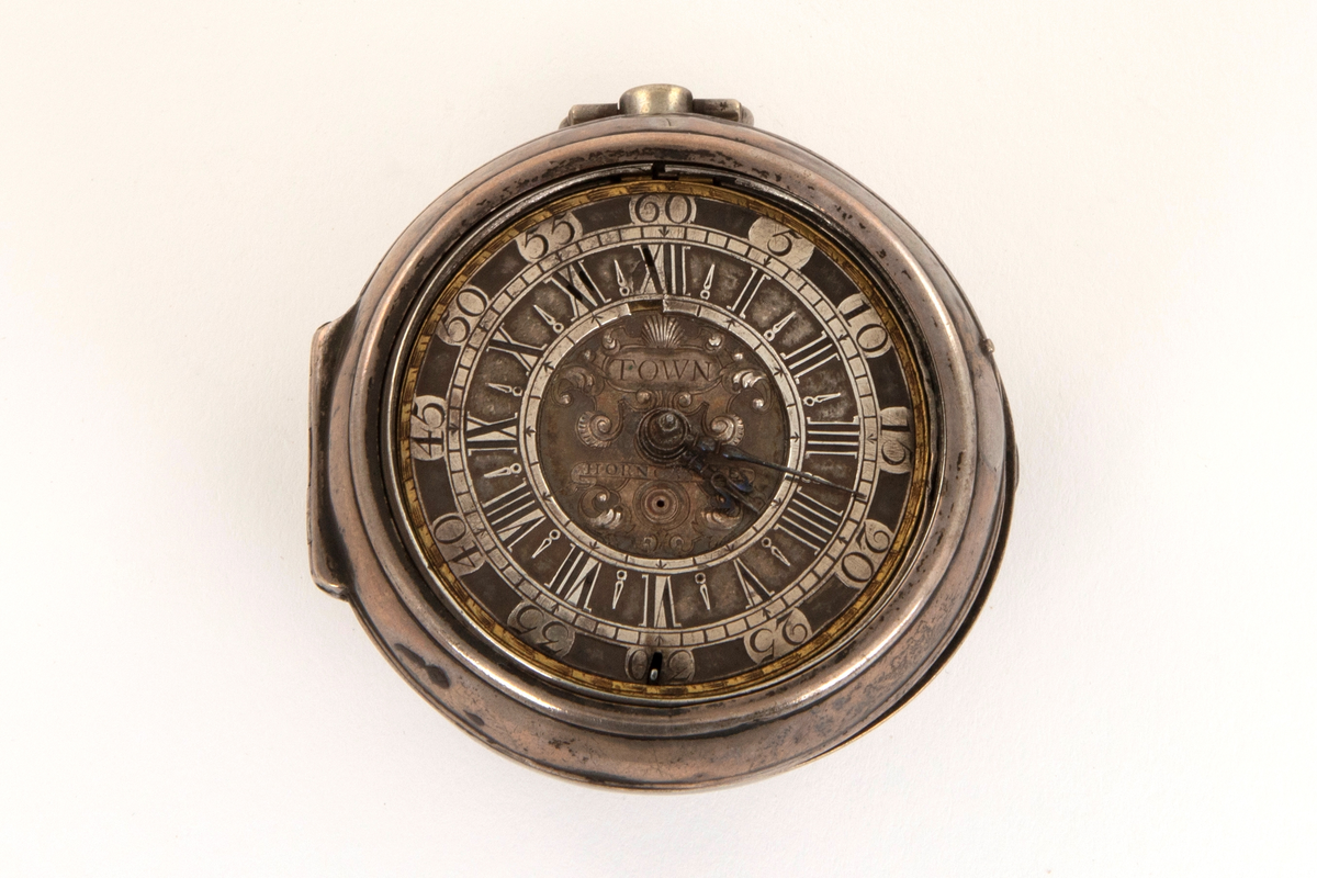 Spindelur med glatt ytterkasse og urkasse av sølv. Sølv tallskive med romerske og arabiske tall og minuttinndeling i relieff. I sentrum kartusj og merket: Town. Horncastle.