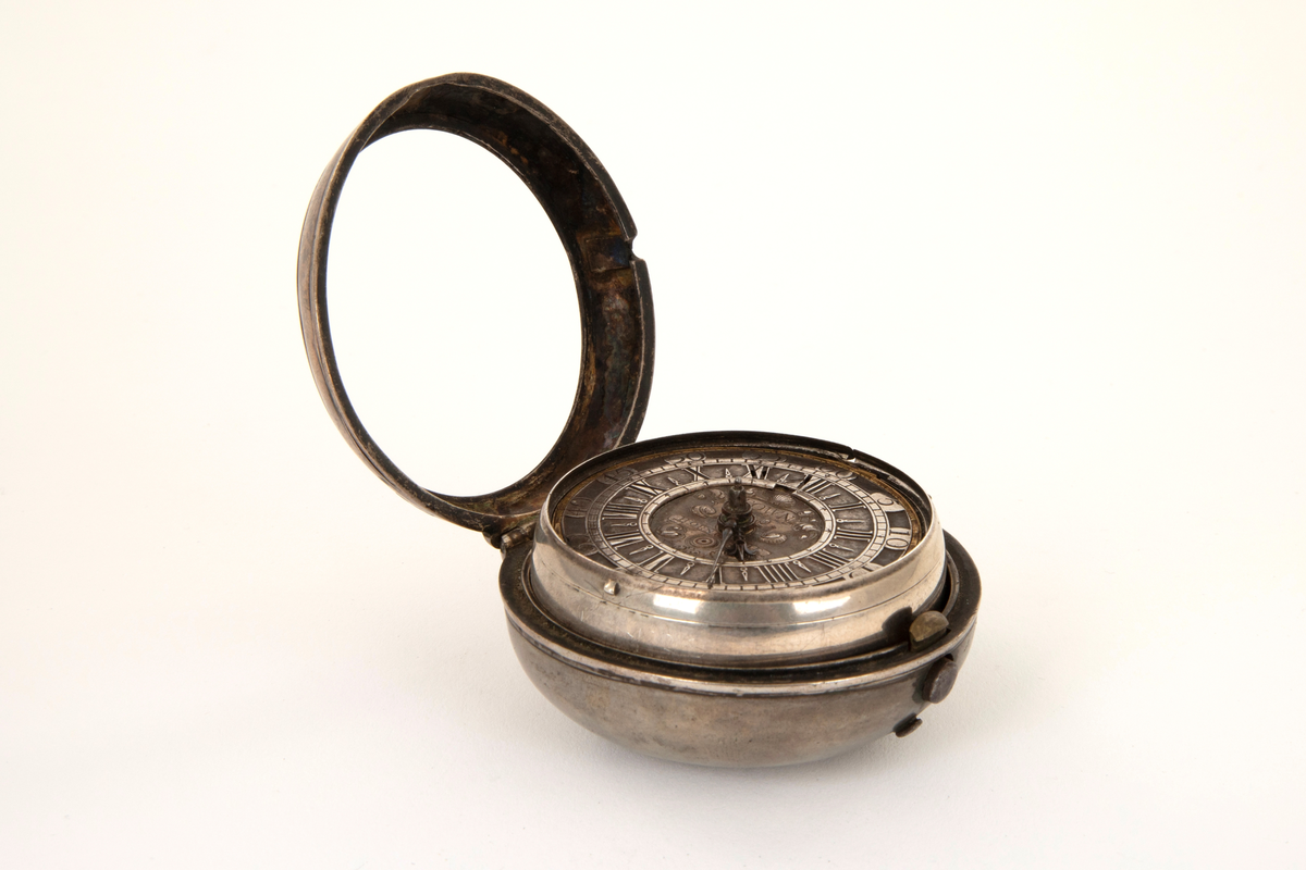 Spindelur med glatt ytterkasse og urkasse av sølv. Sølv tallskive med romerske og arabiske tall og minuttinndeling i relieff. I sentrum kartusj og merket: Town. Horncastle.