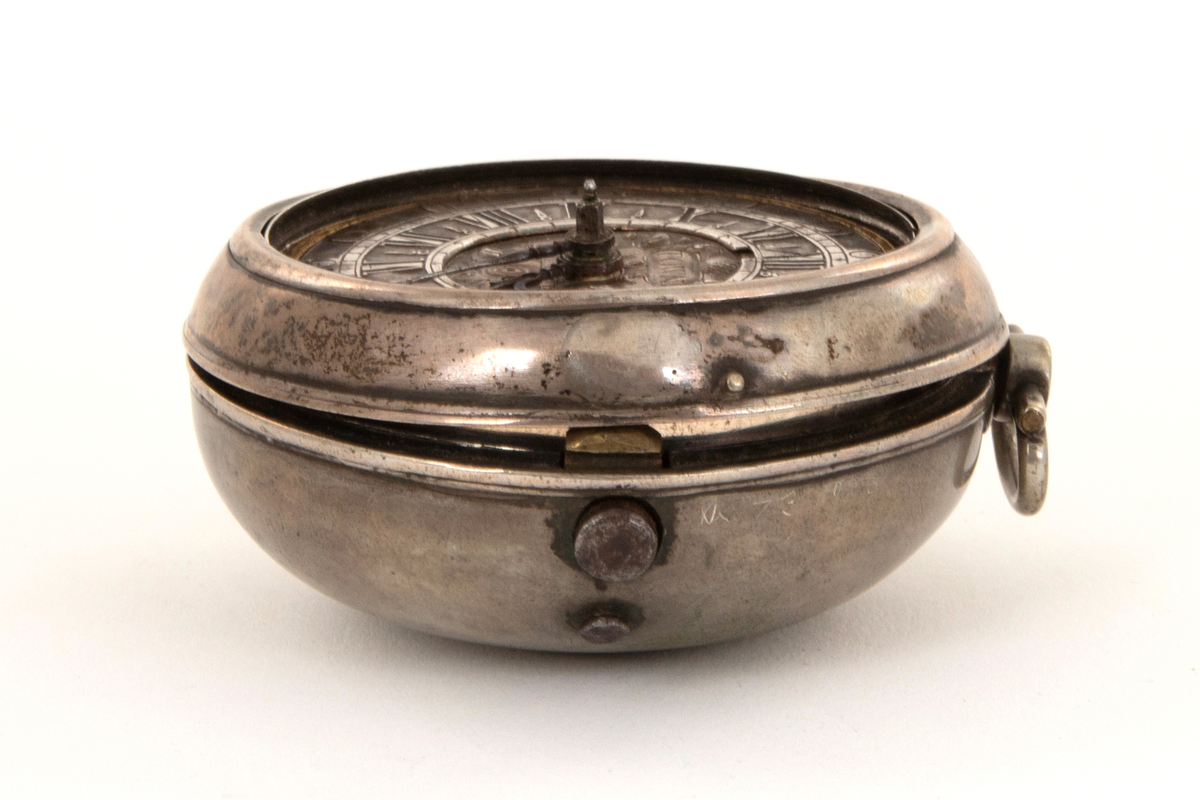 Spindelur med glatt ytterkasse og urkasse av sølv. Sølv tallskive med romerske og arabiske tall og minuttinndeling i relieff. I sentrum kartusj og merket: Town. Horncastle.