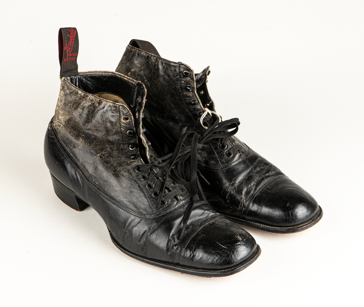 Ett par herrskor i läder som ägts av Karl Fredrik Jernberg, Alfta.  Tidigt 1900-tal. Skorna är svarta med halvhögt skaft. Snörning med både hål och hyskor.