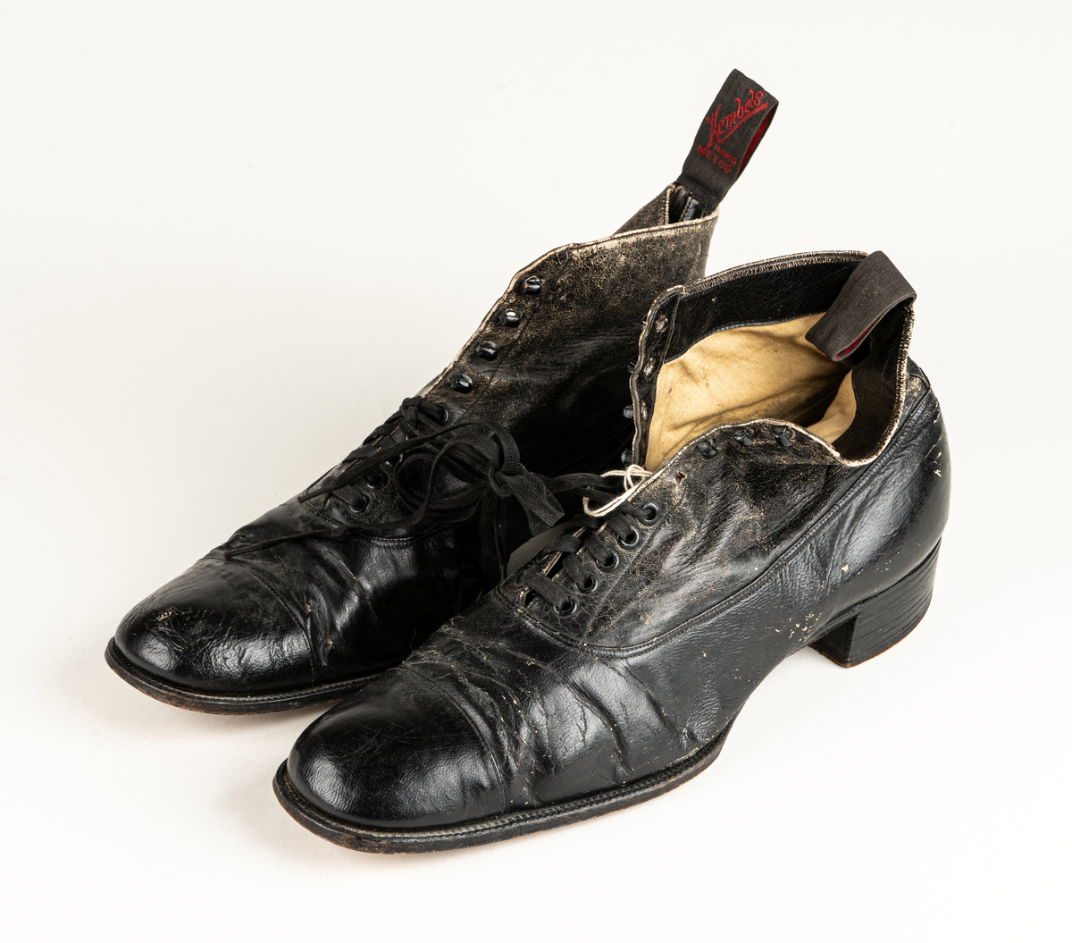 Ett par herrskor i läder som ägts av Karl Fredrik Jernberg, Alfta.  Tidigt 1900-tal. Skorna är svarta med halvhögt skaft. Snörning med både hål och hyskor.