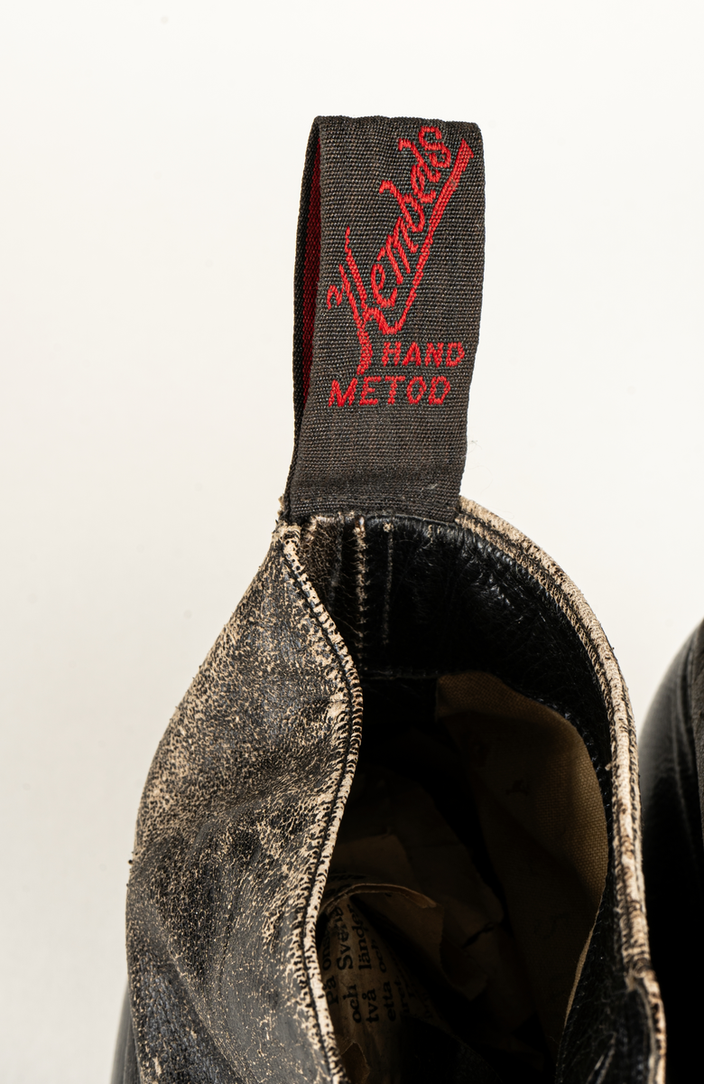 Ett par herrskor i läder som ägts av Karl Fredrik Jernberg, Alfta.  Tidigt 1900-tal. Skorna är svarta med halvhögt skaft. Snörning med både hål och hyskor.