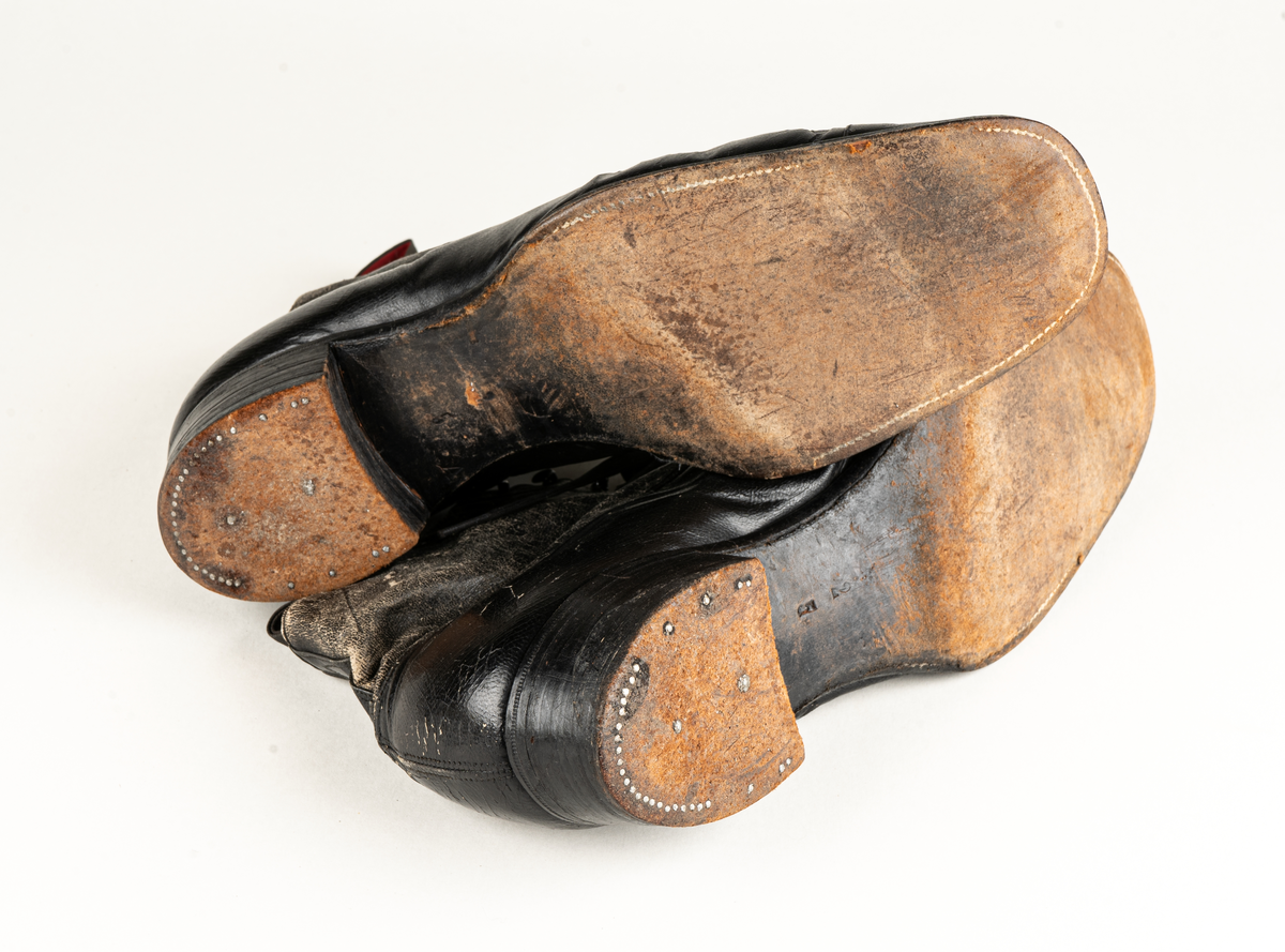 Ett par herrskor i läder som ägts av Karl Fredrik Jernberg, Alfta.  Tidigt 1900-tal. Skorna är svarta med halvhögt skaft. Snörning med både hål och hyskor.