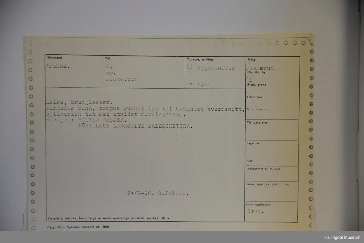 Sirkulær bunn, corpus bunket inn til 4-kantet tverrsnitt. Sylindrisk tut med utvidet munningsrand.