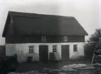 Ladugården med kohus och stall är troligen byggt omkring 1910, kanske lite tidigare med tanke på skavankerna i putsen. Utseendet är typiskt för tiden. Vad Friberg höll på med för något på gårdsplanen kan man undra?